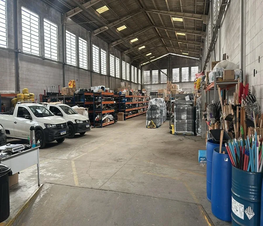 Interior do centro de distribuição da CUBEX: galpão com prateleiras, paletes e veículos de entrega.